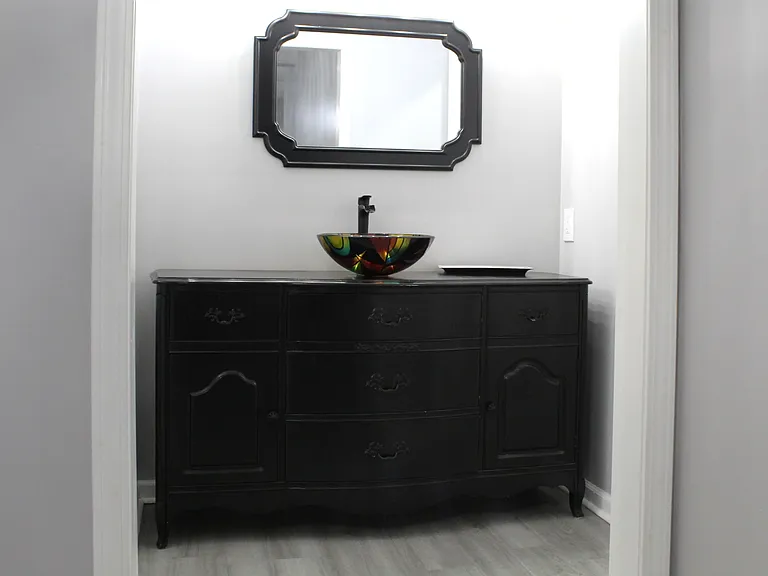 The powder room vanity sink and mirror are located outside the shower/toilet space.