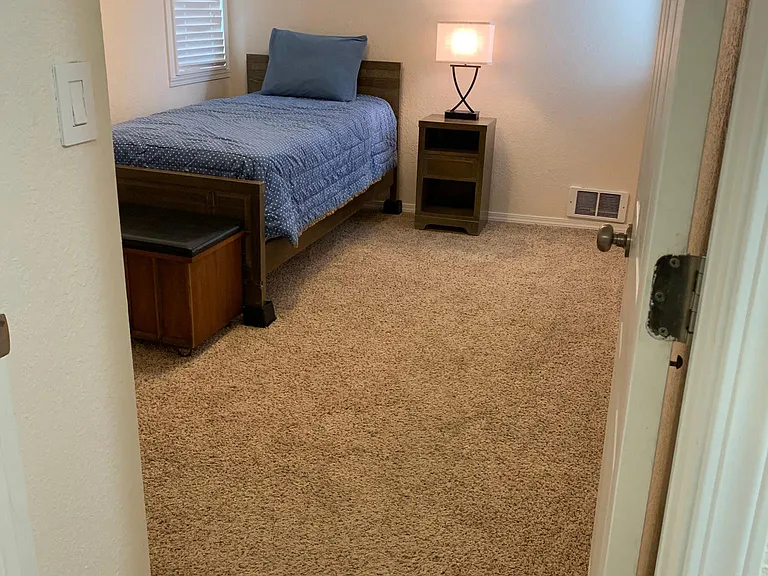 1st bedroom furnished with twin bed/mattress/nightstand/usb table light. Bed on risers to allow for underbed storage units. End of bed sitting/storage chest. Fully carpeted. 2 Levoler blinds.
