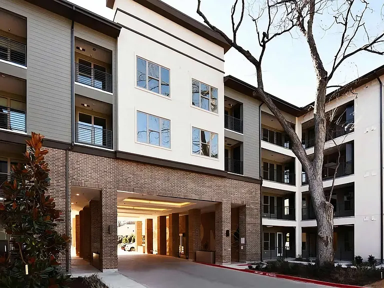 Covered Apartment Entry with Warm Brick Detailing and Balcony Views
