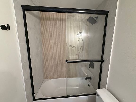 Two tone tiled showers with sliding glass shower doors.
