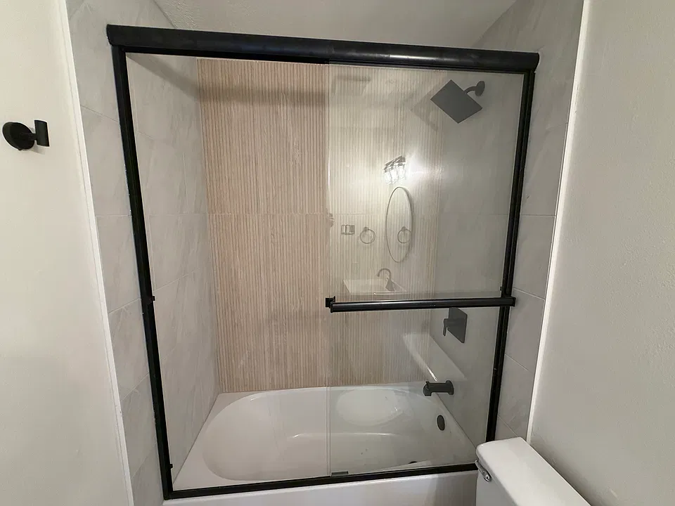 Two tone tiled showers with sliding glass shower doors.