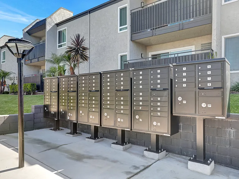 A row of mailboxes are lined up on a sidewalk.