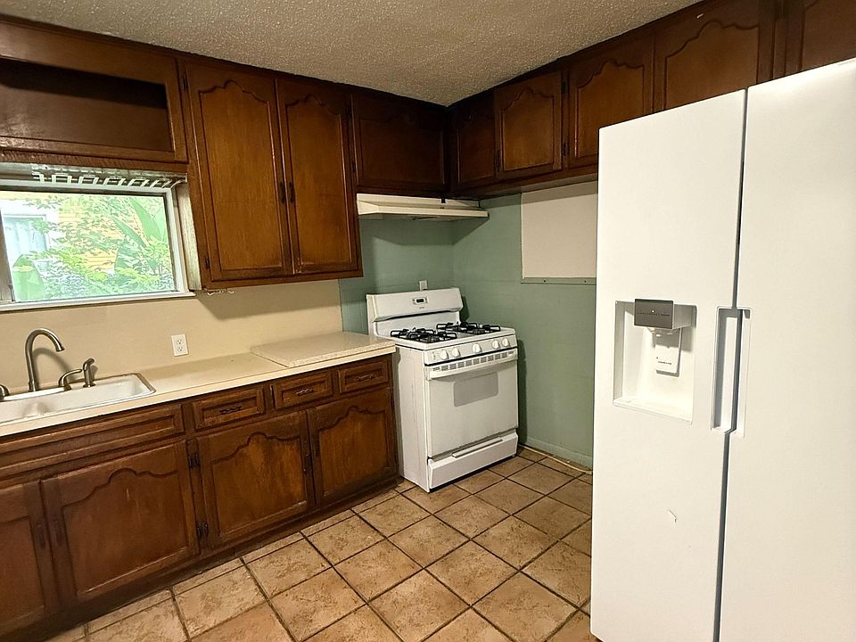 Kitchen with ample wood cabinetry, tile flooring, and a full appliance package including refrigerator and gas range.