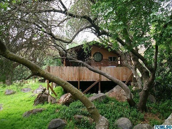 END OF HOME WITH WRAP AROUND DECKING FROM THE DRIVING ENTRANCE.