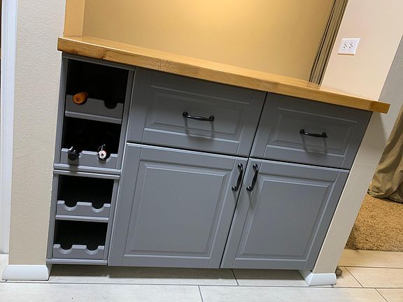 Island with butcher block counter top and wine rack. Kitchen floors are porcelain tile.