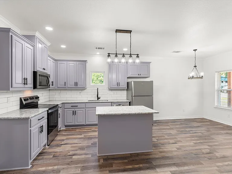 Kitchen featuring lavender cabinetry, granite countertops, a white subway tile backsplash, stainless steel appliances, and wood-finish flooring