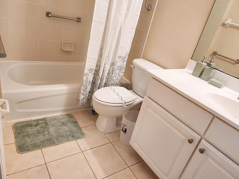 Full bathroom with tub/shower combo, tiled surround, and a wide vanity with storage and a large mirror.