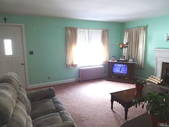 Living room. Hardwood under carpet. Wood burning fpl. with raised hearth.  Newer front door. There is an air lock entry (small foyer) on the other side of the door.