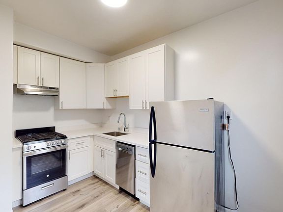 Kitchen with multiple cabinets, refrigerator, stove, range hood, dishwasher and sink