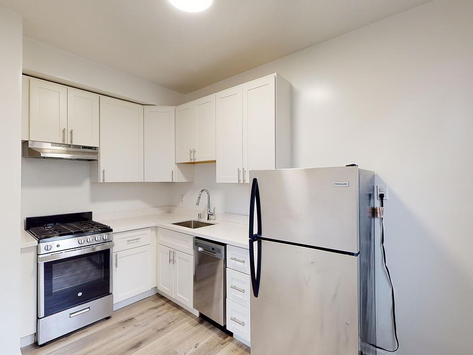 Kitchen with multiple cabinets, refrigerator, stove, range hood, dishwasher and sink