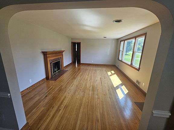 19x13.5 ft Living room with refinished wood floors, fireplace and new paint.