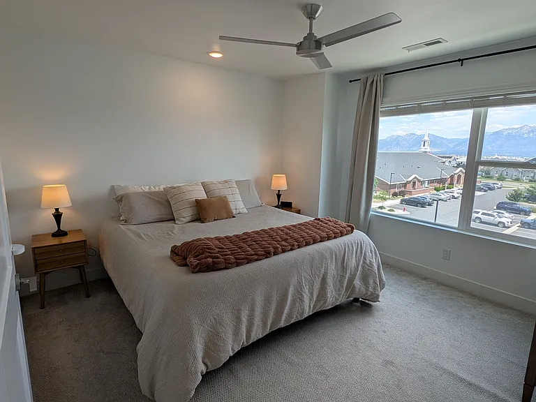 Primary bedroom with large window and ceiling fan
