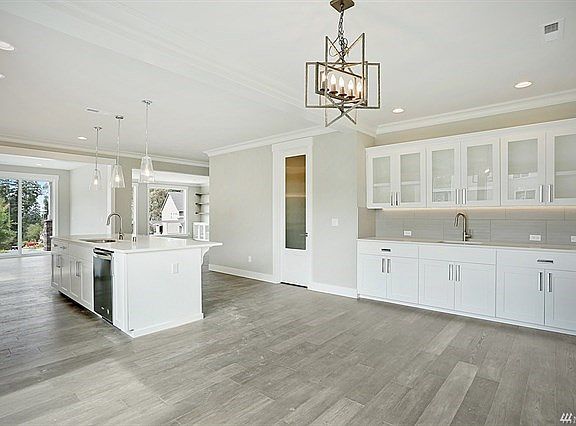 Eating area next to kitchen features wet bar with additional sink and more cabinets for storage