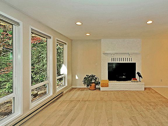 The living room has a wood burning fireplace and large picture windows that highlight the serene fro