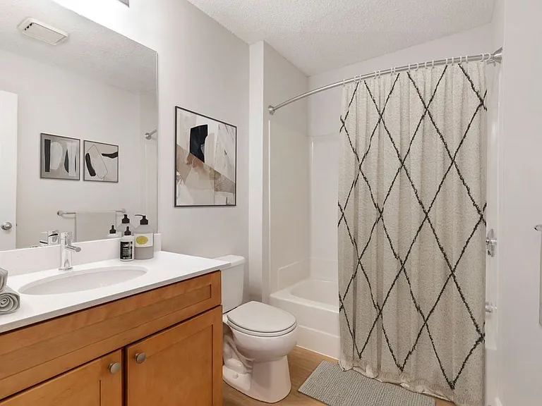 Renovated Package I bath with white quartz countertops, maple cabinetry, and hard surface flooring
