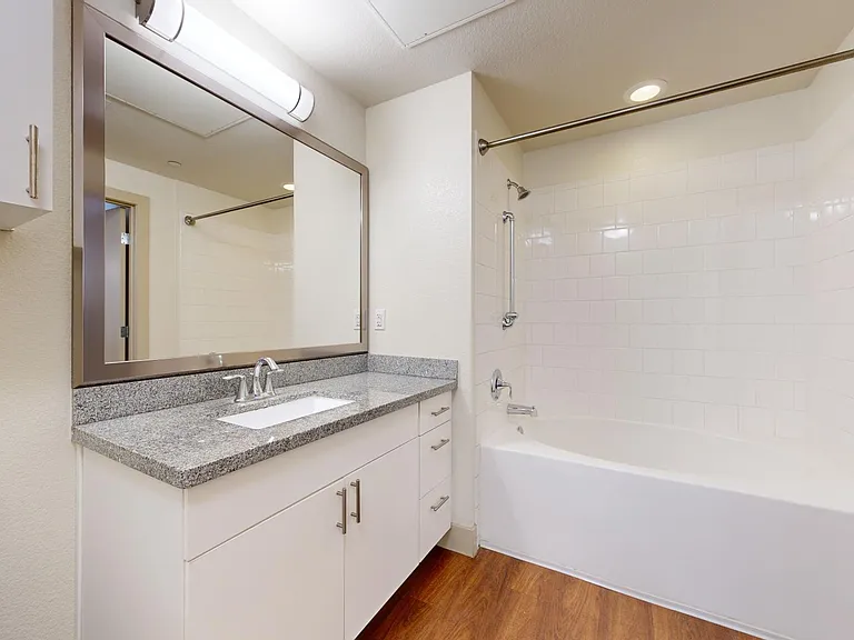 Apartment bathroom with large soaking tub and wood-style flooring.