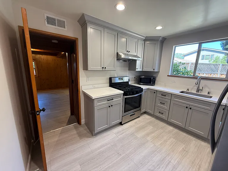 Efficient kitchen is equipped with stainless steel appliances and soft-close cabinetry and quartz countertop.
