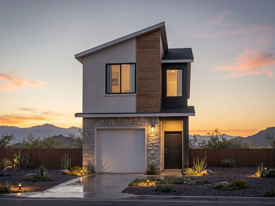 Modern two-story house with stone and wood accents, lit warm lights, and desert landscaping at sunse