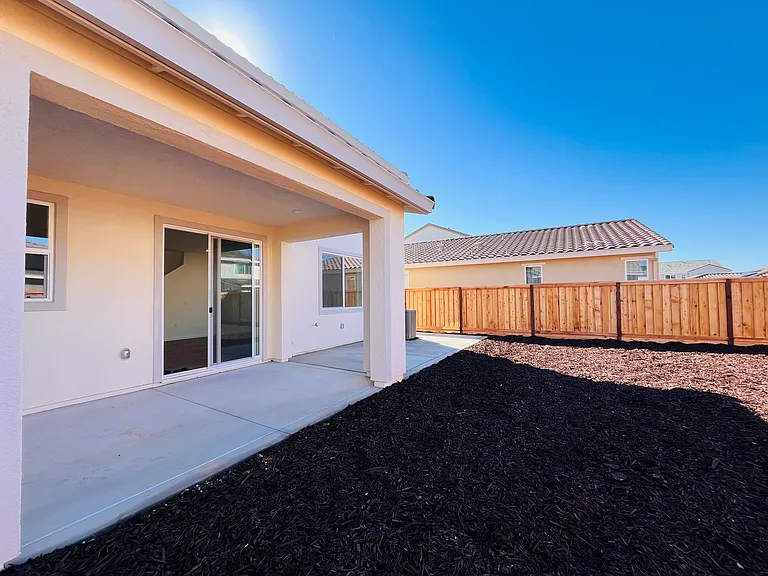 Backyard with extended concrete and low maintenance mulch