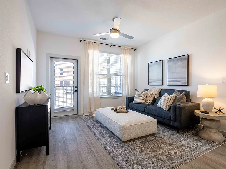 This living room in the Garrett Parker B1 floor plan includes a private patio door, a ceiling fan, and space for a sofa and accent furniture.