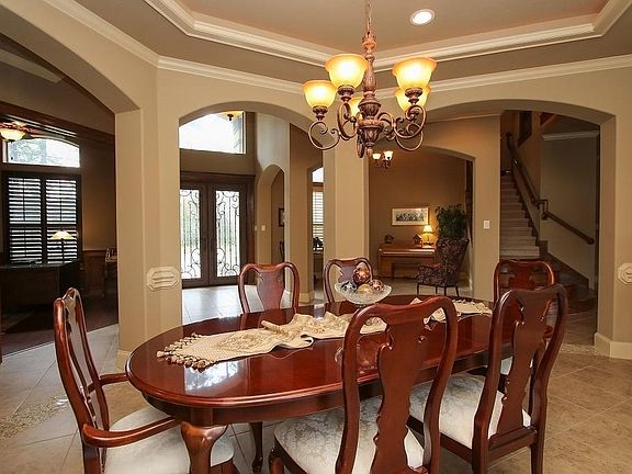 Formal Dining Room with tray ceiling, rope lighting, elegant chandelier & beautiful arches. View back to entry, Living Room , Study and staircase.