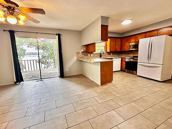 Spacious open-concept kitchen w/ updated granite counter tops, sink & faucet, and dining area w/ lake view & deck access