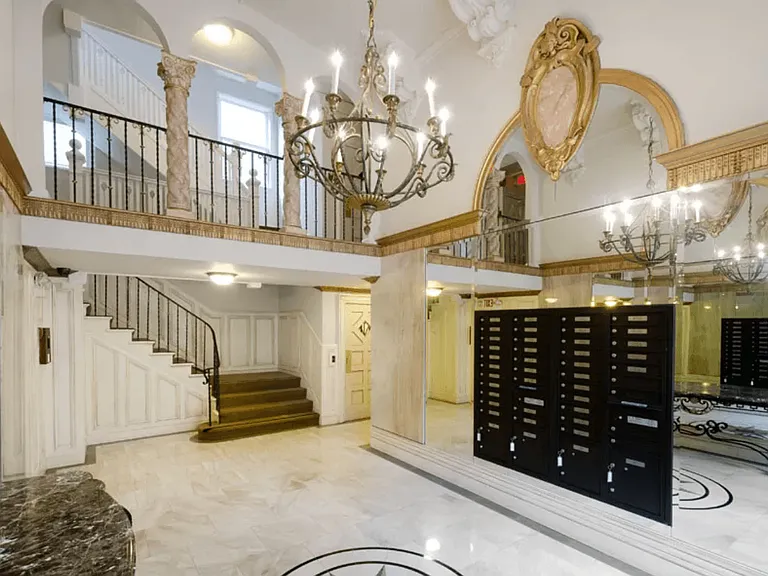 Elegant lobby with a grand staircase, a chandelier, and Victorian-style interior design