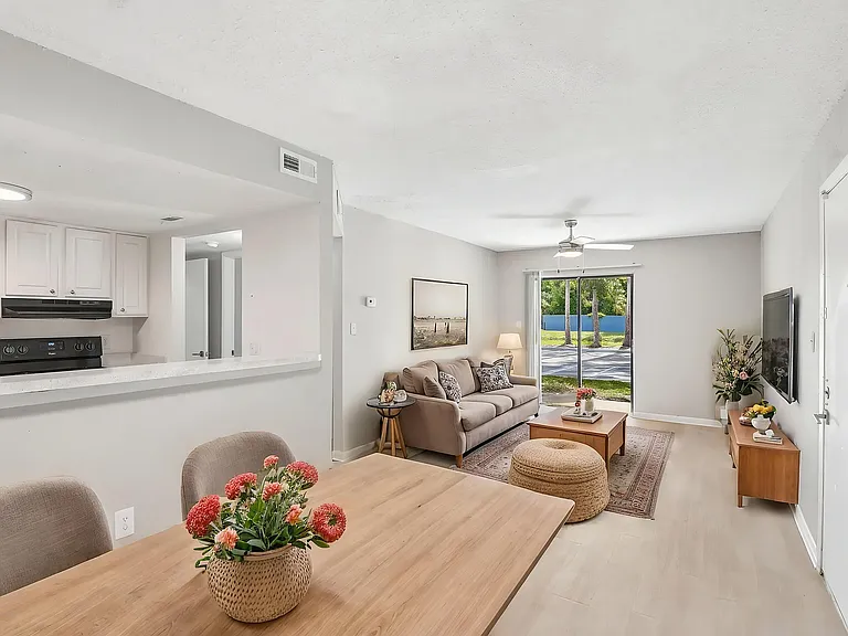 Inviting open-plan living space with modern kitchen and cozy seating area, featuring abundant natural light from large windows.