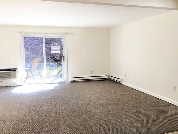 carpeted living room with AC unit and baseboard heat.