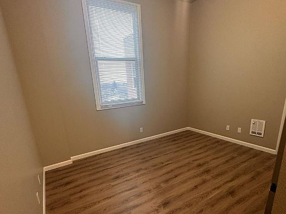 Bright, spacious room with elegant wood flooring and a large window providing natural light. Bright, spacious room with elegant wood flooring and a large window providing natural light.