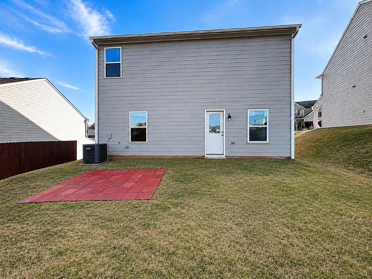 Back of property with patio area, central A/C, and spacious lawn