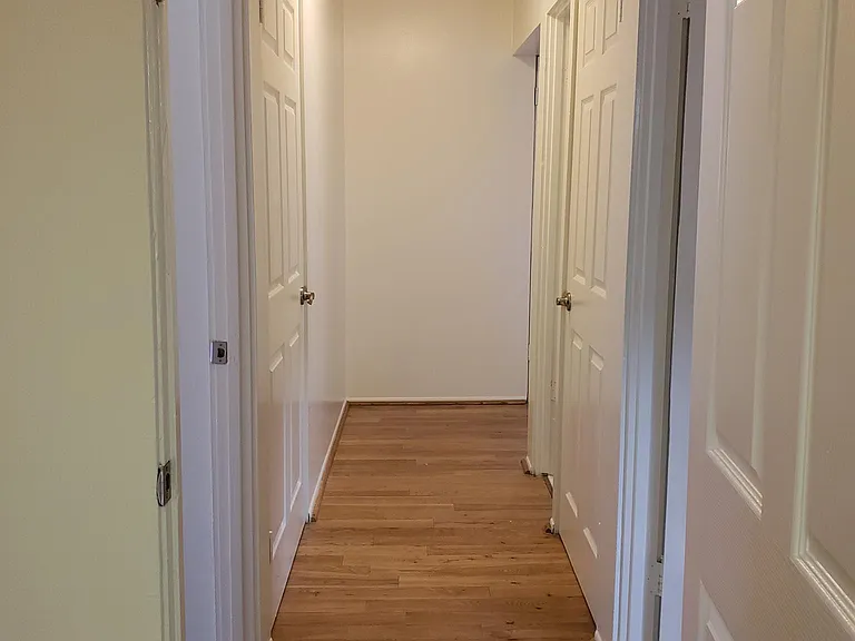 Looking in the hall way from the garage, two storage closets on each side of hallway, two bedroom doors on opposite sides of hallway and then restroom