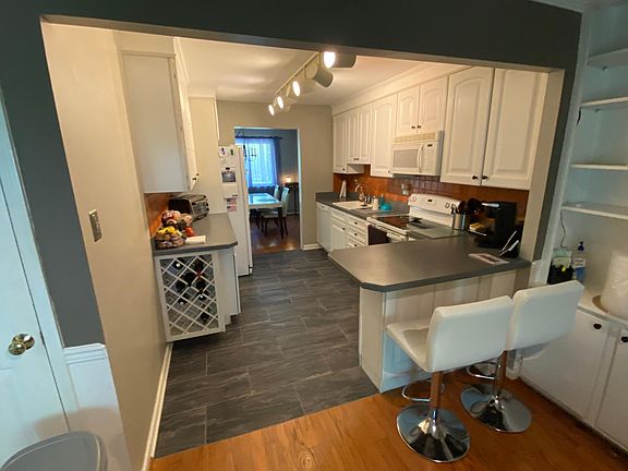 View of Kitchen from Den. Plenty of storage with wine rack and small breakfast bar on right side.