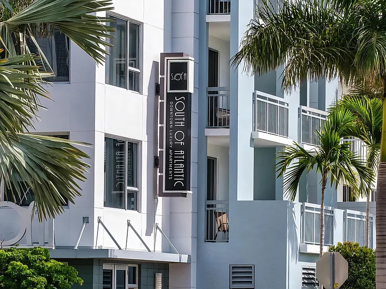 South of Atlantic Apartment Entrance Framed by Palm Trees and Custom Sign