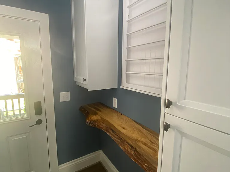 Close up of Mud/laundry room (off side porch entrance): live edge counter for folding clothes, project work; rack for air drying clothing; storage. Storage space for kitchen rolling island underneath counter.