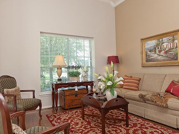 Another view of the living room showing the high ceilings and window blinds.