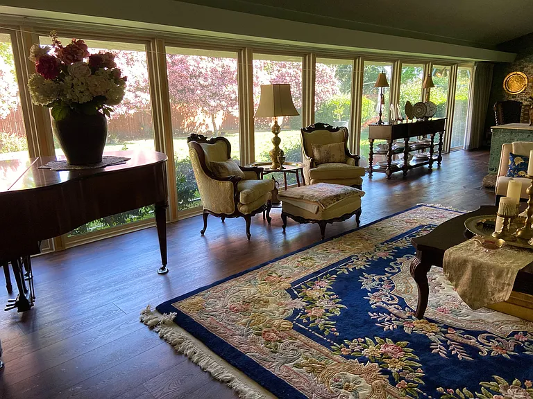 Spacious living area with hardwood floors, a large picture-window wall, and comfortable seating with views of the yard.