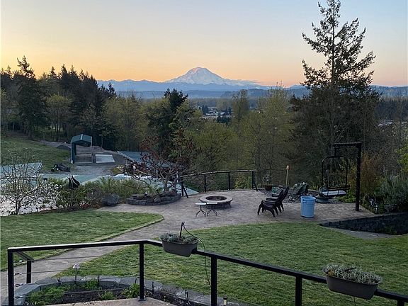 The View of Mt Rainier, the fire pit, bubble rock fountain area from the large side patio that has stamped concrete