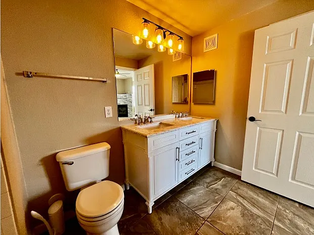 Ensuite bathroom for second bedroom with double vanity and granite countertops.
