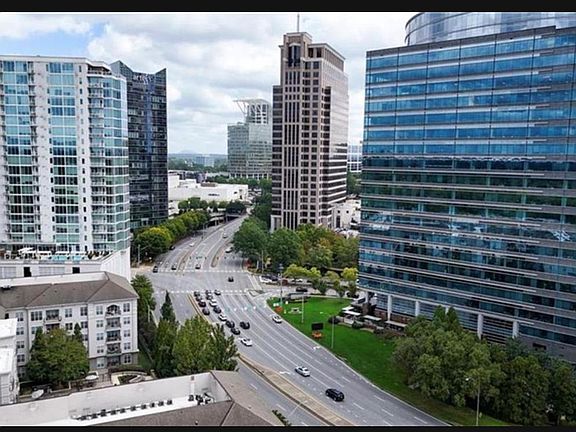 Elevated exterior view of a city setting with nearby high-rises, tree-lined streets, and convenient access to major roads.