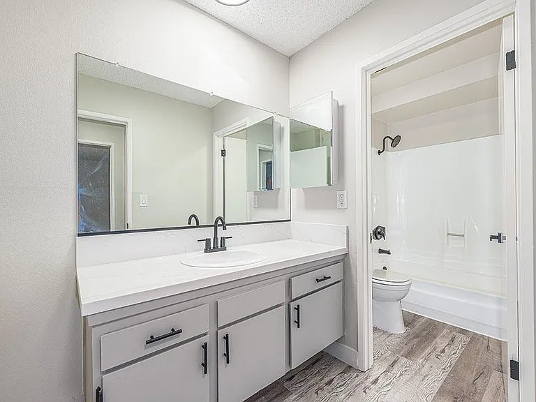 Modern styled bathroom vanity with view to full bathroom.