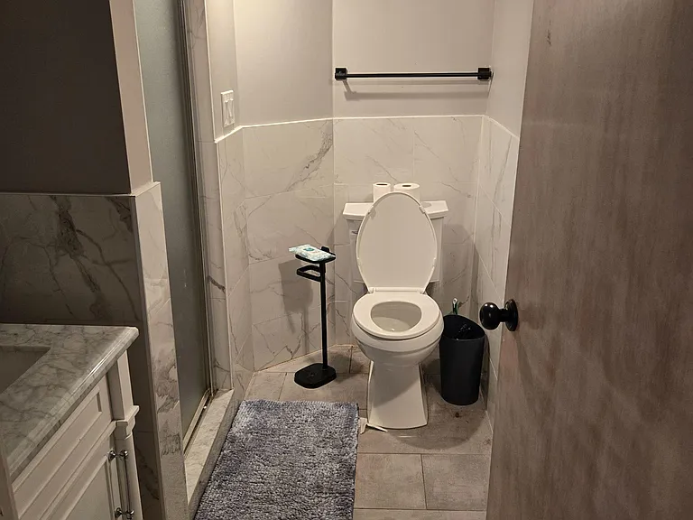 Full bathroom with tiled shower, updated vanity, and open wall space for towels and storage.