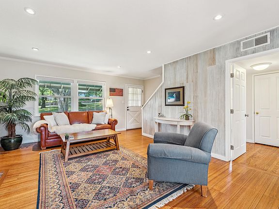 Living room with hardwood floor, recessed lighting and wood fire place.