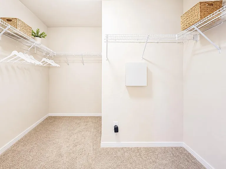 Spacious walk-in closet with wraparound wire shelving and hanging space for easy organization and extra storage.