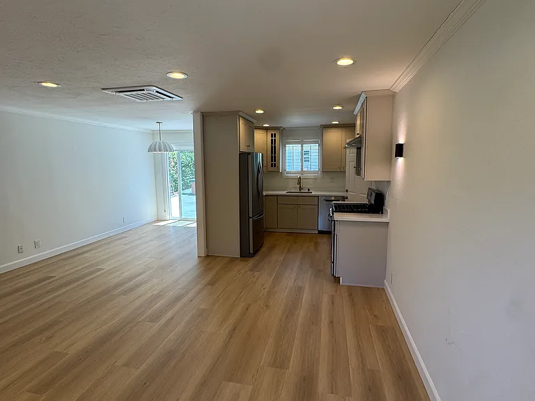 Living room facing kitchen, dining area, and patio with access to the spacious private backyard and spa.