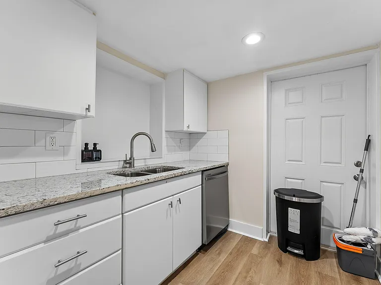 Galley-style kitchen with granite-look counters, subway-tile backsplash, ample cabinetry, and stainless dishwasher.