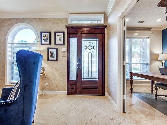 Front door entry shows location of the home office or 5th bedroom. 2 inch blinds on windows and tiled flooring. Note the artistic painted walls. This front door locks itself!