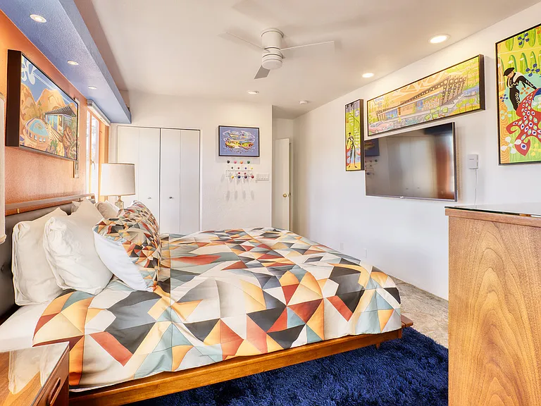 Master bedroom with flat screen Smart TV and vintage dresser and night tables.