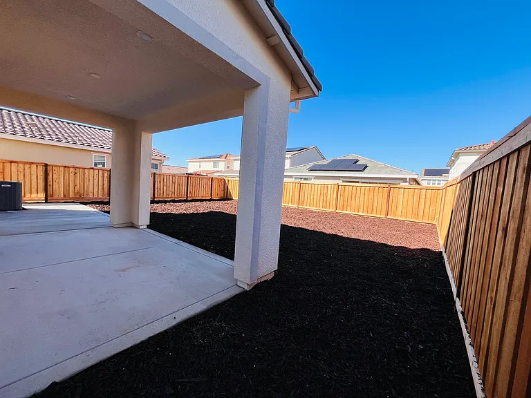 Backyard with extended concrete and low maintenance mulch