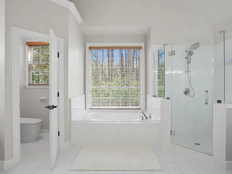 Clean, spacious primary bathroom with soaking tub, glass shower, and thoughtfully upgraded modern features